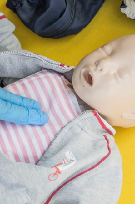 A person demonstrates infant CPR on a manikin, highlighting first aid techniques.